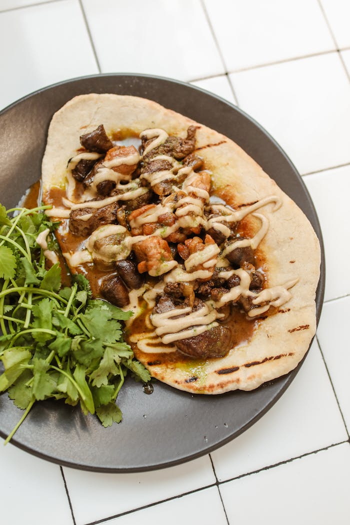 Savory Jerusalem mixed grill served on a pita with fresh herbs and sauce, a traditional Jewish cuisine dish.